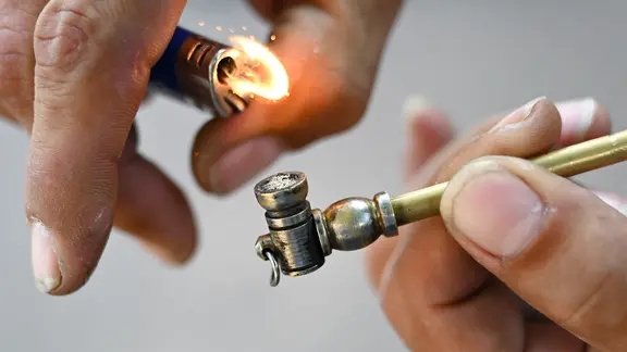 Eine Crackpfeife wird mit einem Feuerzeug angezündet.
