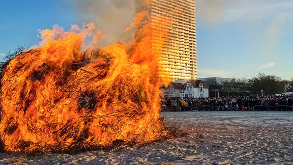 Menschen bewundern das Osterfeuer in Travemünde.