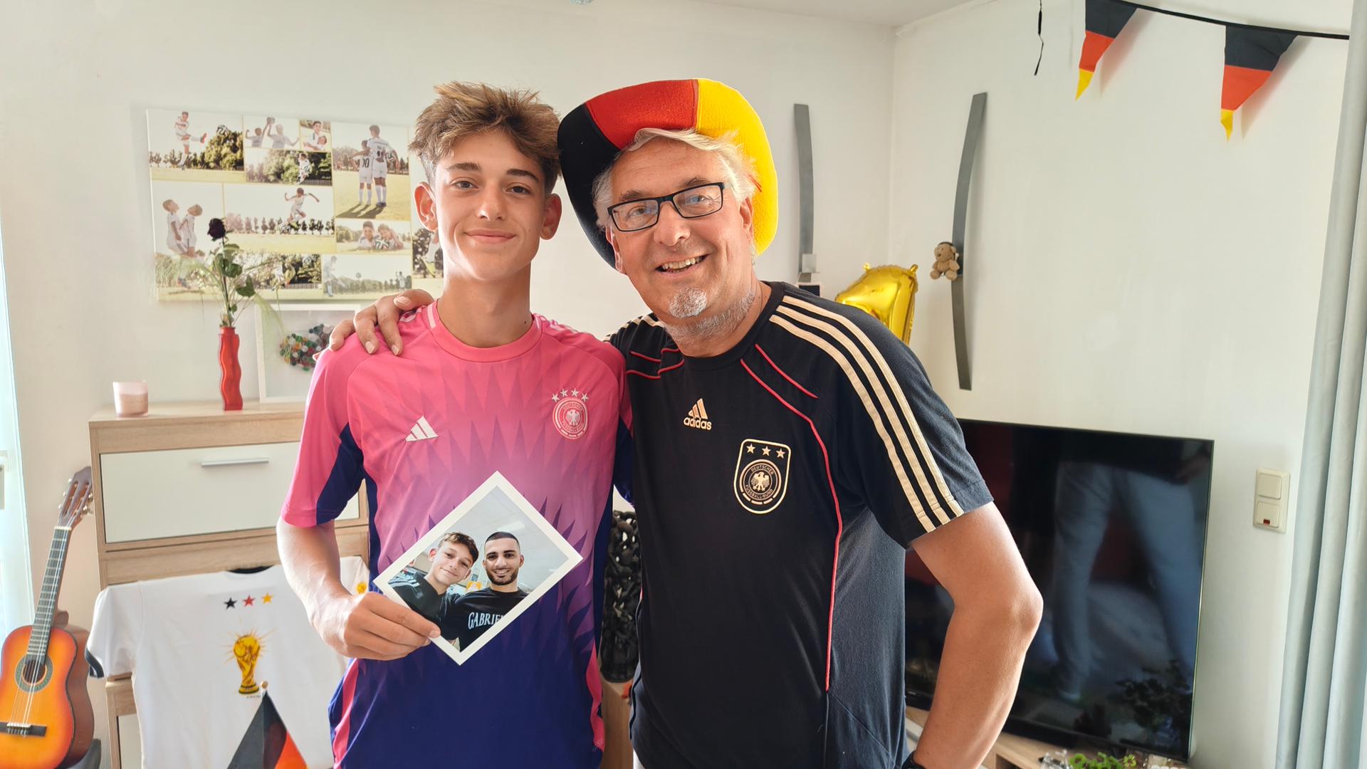 In Trikots der deutschen Nationalmannschaft stehen Vater und Sohn im Wohnzimmer. | NDR, Sebastian Duden