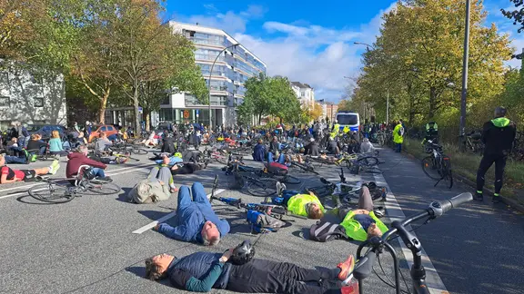 Bei einer Mahnwache in Hamburg-Rotherbaum liegen Menschen auf der Straße