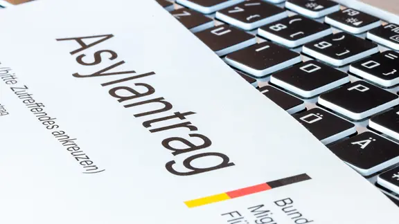 Ein Formular auf Asylantrag in Deutschland liegt auf einer Tastatur.