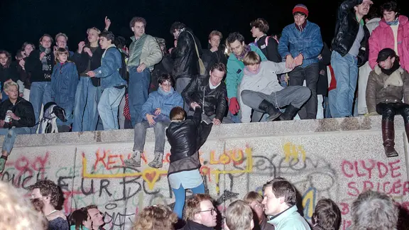 Menschen feiern am 10. November 1989 vor und auf der Mauer in Berlin den Mauerfall.