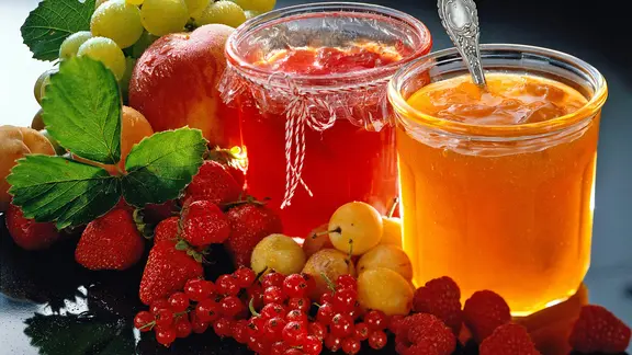 Gläser mit selbstgemachter Marmelade und frischen Früchten.