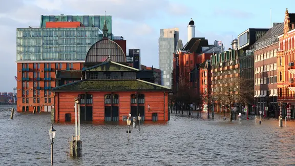 Der Fischmarkt wird bei einer Sturmflut überflutet. | Christian Charisius/dpa, Christian Charisius Der Fischmarkt wird bei einer Sturmflut überflutet.