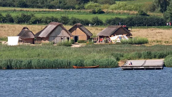 Die rekonstruierte Siedlung und der Landesteg in Haithabu vom Wasser aus gesehen.