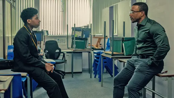 Ein Teenager-Junge sitzt einem älteren Mann in angespannter Haltung gegenüber - Szene aus der "Netflix"-Serie "Adolescence" mit den Schauspielern Amari Jayden Bacchus und Ashley Walters als Polizist