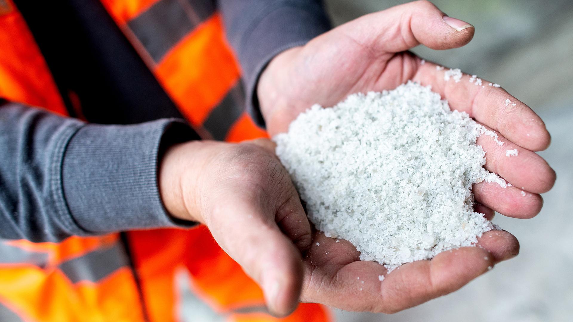 Ein Mitarbeiter der Stadt Hildesheim hält Streusalz in den Händen. | picture alliance, Hauke-Christian Dittrich