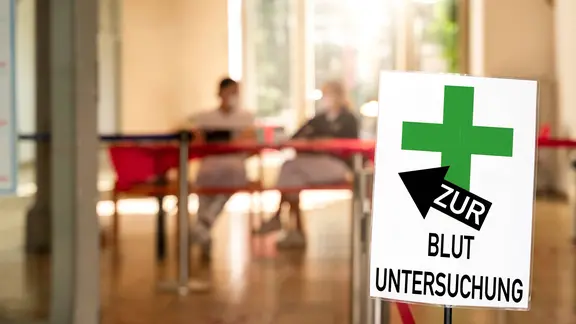 "Zur Blutuntersuchung" steht auf einem Schild einer Arztpraxis beim Hausarzt.