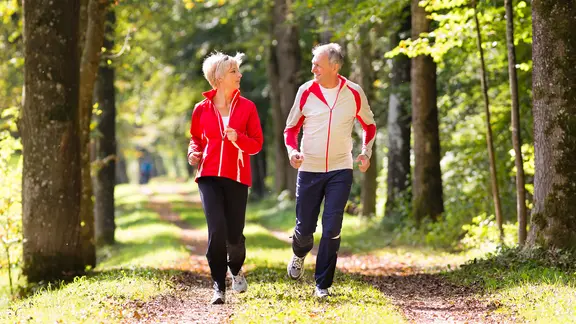 Mann und Frauen joggen im Wald.