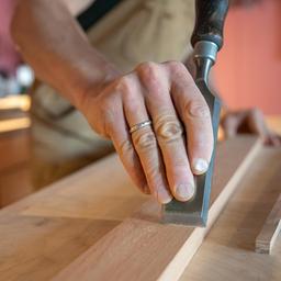 Ein erfahrender Tischler bearbeitet geschickt ein Stück Holz.