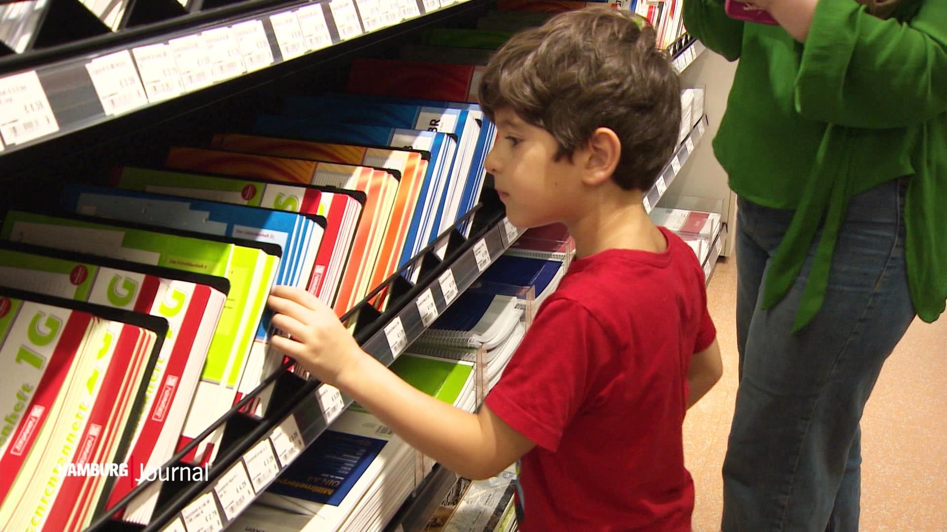 Ein kleiner Junge schaut sich Schulhefte in einem Laden an. | Screenshot