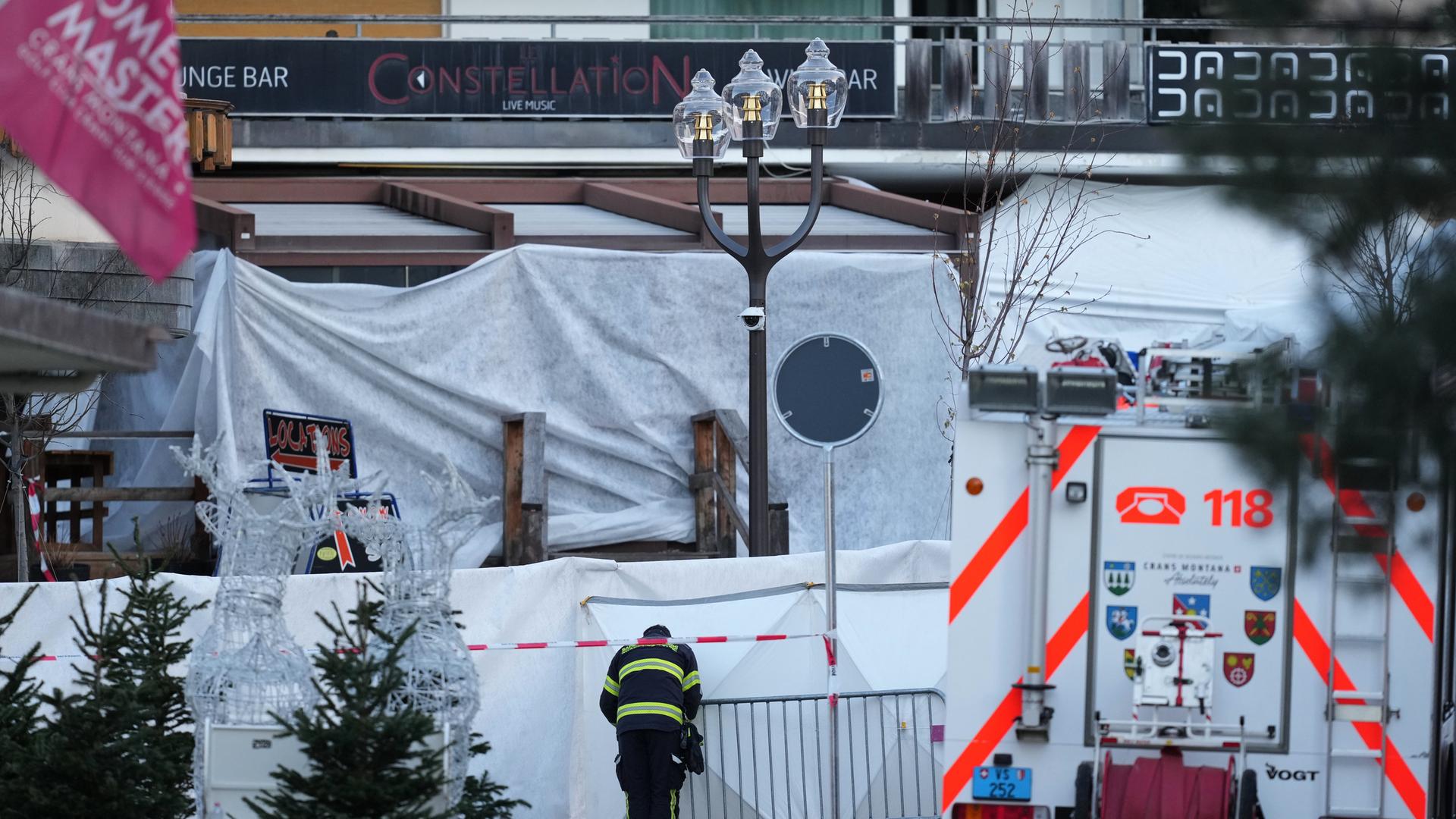 Ein Feuerwehrmann vor der abgeriegelten Bar Le Constellation in Crans-Montana in den Schweizer Alpen | AP/dpa, Antonio Calanni