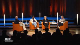 Bei einer Podiumsdiskussion sitzen vier Personen auf Stühlen nebeneinander.