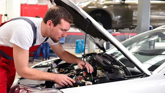 Ein Automechaniker in einer Werkstatt repariert ein Fahrzeug.