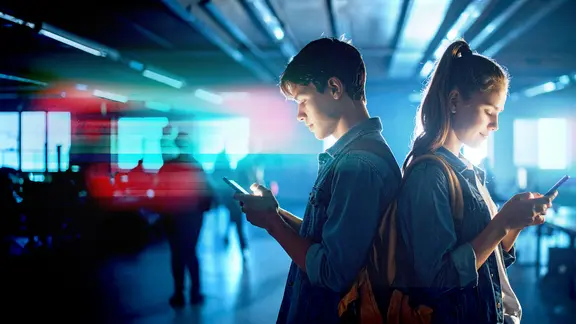 Bildmontage: Zwei Jugendliche schauen in ihre Handys. (KI-generiert)