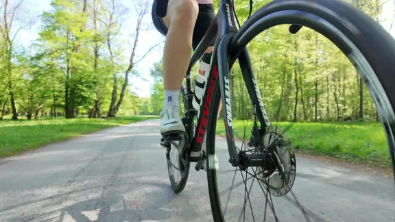 Eine Frau fährt Rennrad. Nahaufnahme des Rades auf der Straße.