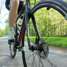 Eine Frau fährt Rennrad. Nahaufnahme des Rades auf der Straße.