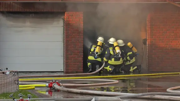 Einsatzkräfte der Feuerwehr löschen eine brennende Garage.
