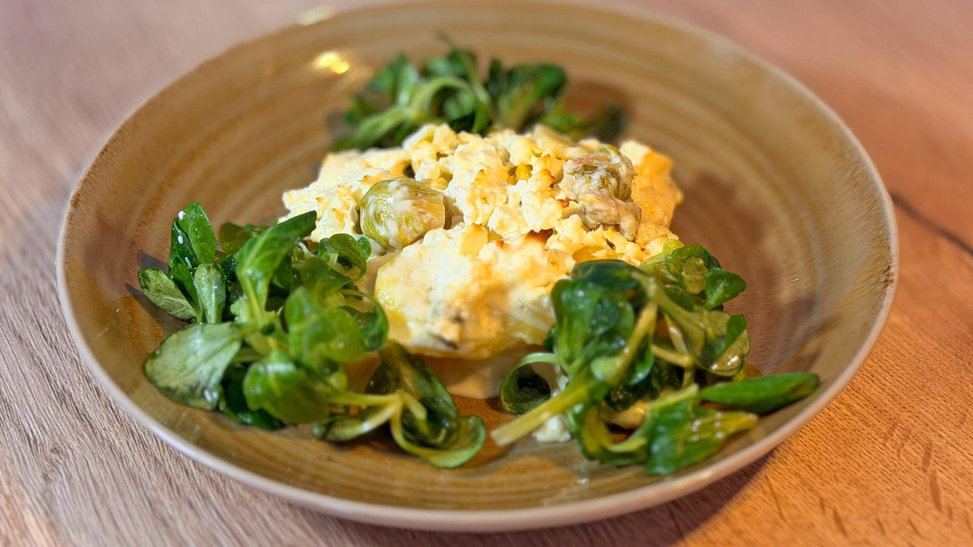 Rosenkohl-Kartoffelgratin und Feldsalat auf einem tiefen Teller angerichtet | NDR, Lisa Knittel