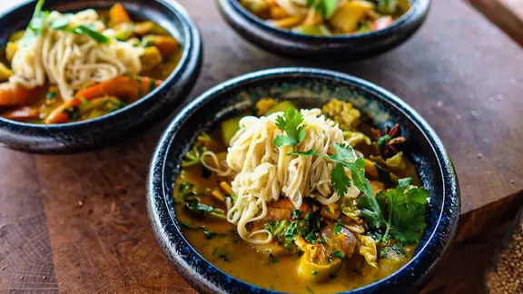 Kürbis-Curry mit Nudeln auf einem Teller serviert.