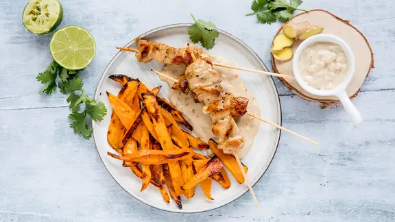 Ein Teller mit Geflügelspieße und Süßkartoffelspalten und ein Schälchen mit Erdnusssoße stehen auf dem Tisch. | NDR, Claudia Timmann Ein Teller mit Geflügelspieße und Süßkartoffelspalten und ein Schälchen mit Erdnusssoße stehen auf dem Tisch.