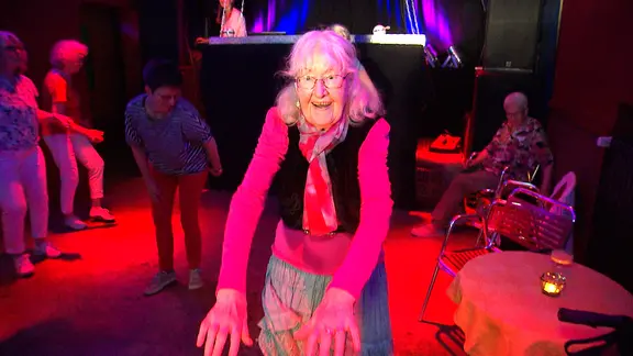 Eine alte Dame tanzt in einem Club.