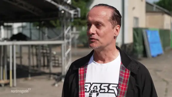 DJ Alex Christensen im Interview auf einem Platz.