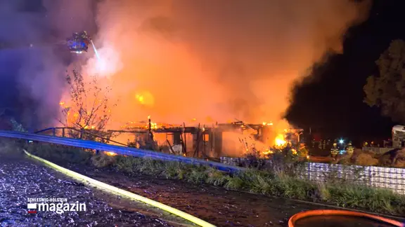 Ein brennendes Haus während Löscharbeiten der Feuerwehr