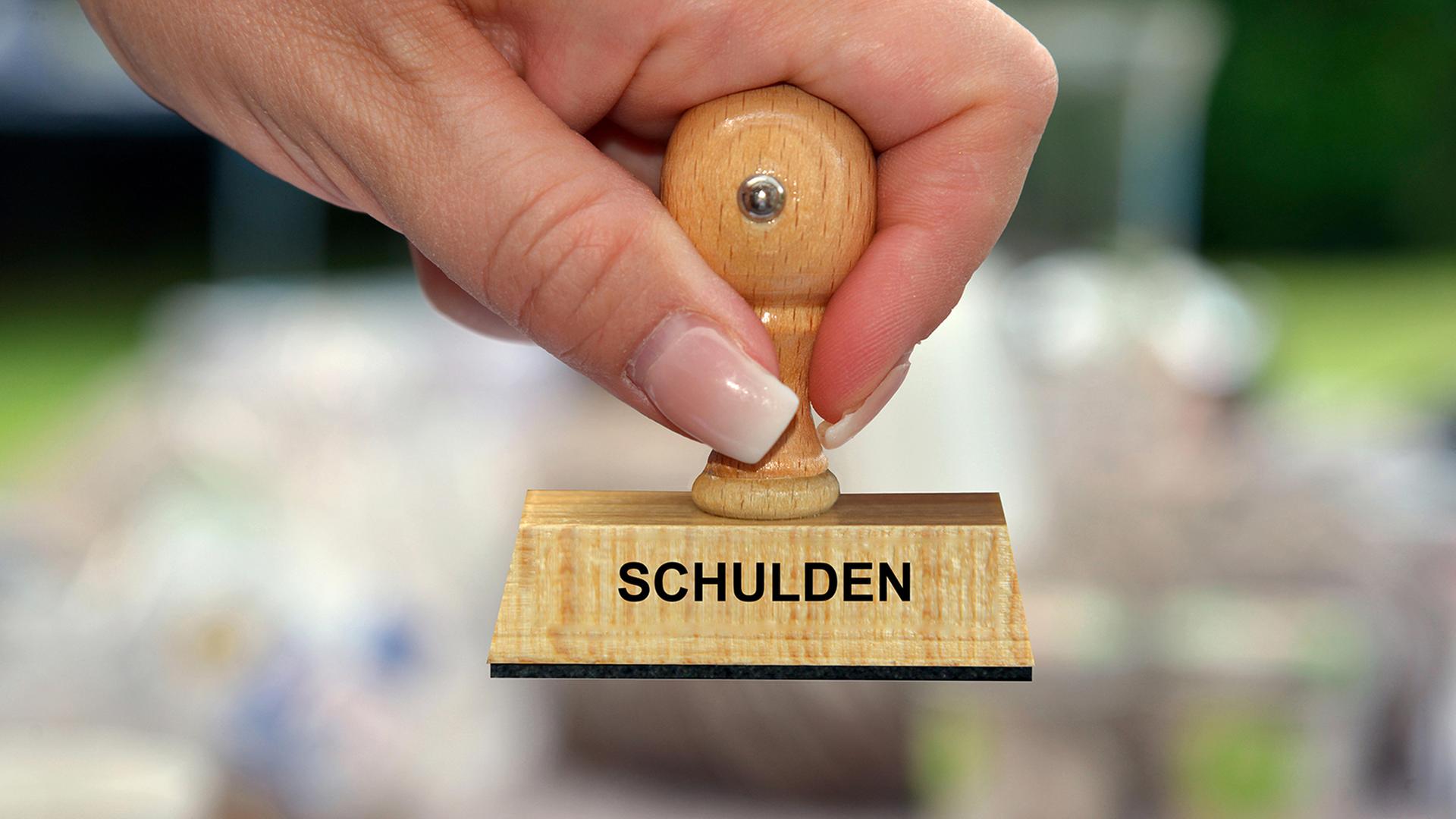 Eine Person hält einen Holzstempel mit der Aufschrift 