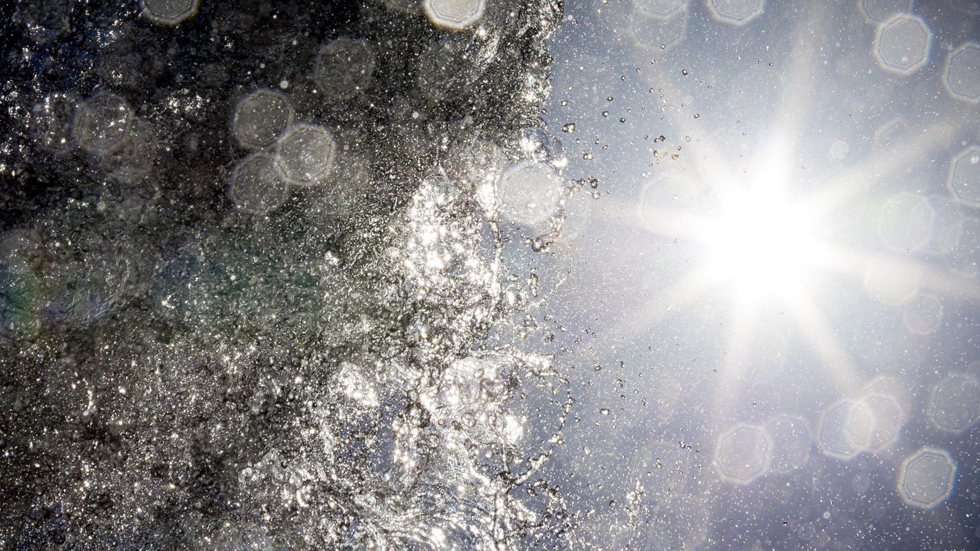 Die Sonne scheint bei hochsommerlichem Wetter hinter dem Klaus-Bahlsen-Brunnen auf dem Platz der Menschenrechte in Hannover. | Moritz Frankenberg/dpa