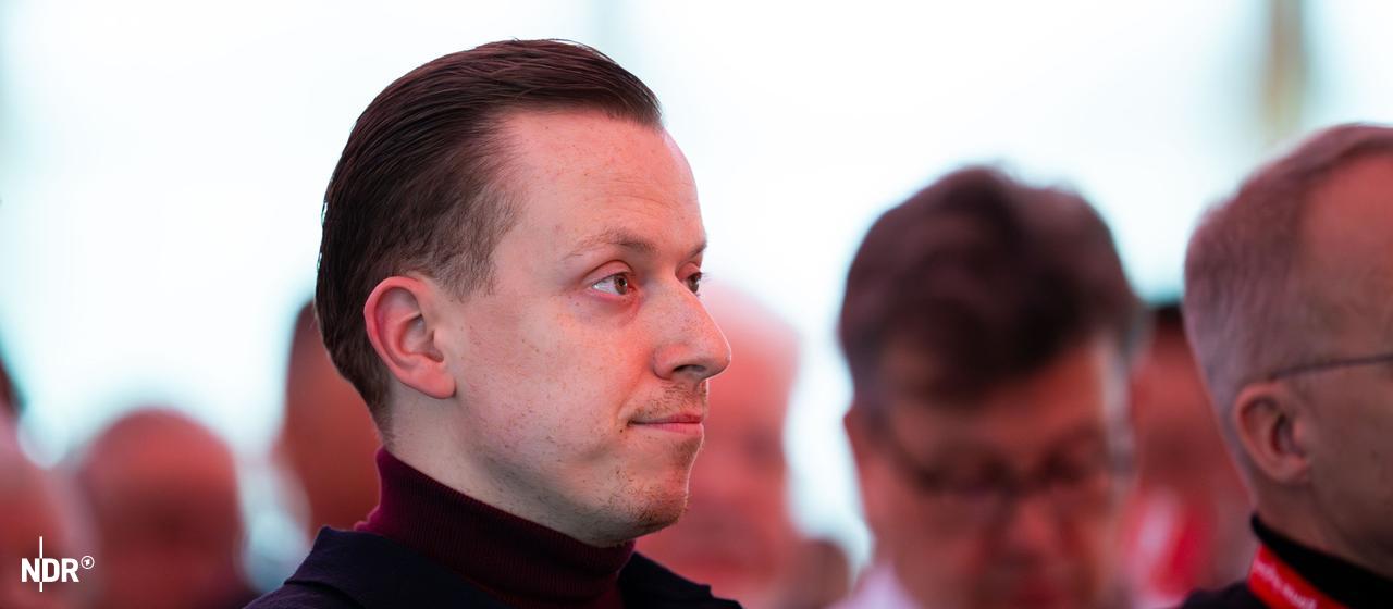 Adis Ahmetovic hört nachdenklich bei einer Veranstaltung zu.