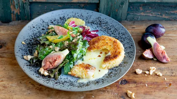 Gebackener Camembert mit Salat auf einem Teller serviert.