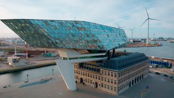 Das Havenhuis in Antwerpen – ein futurischer Glasbau von Zaha Hadid über einem historischen Feuerwehrhaus, Sinnbild für den Wandel des Hafens zur Innovationsdrehscheibe.