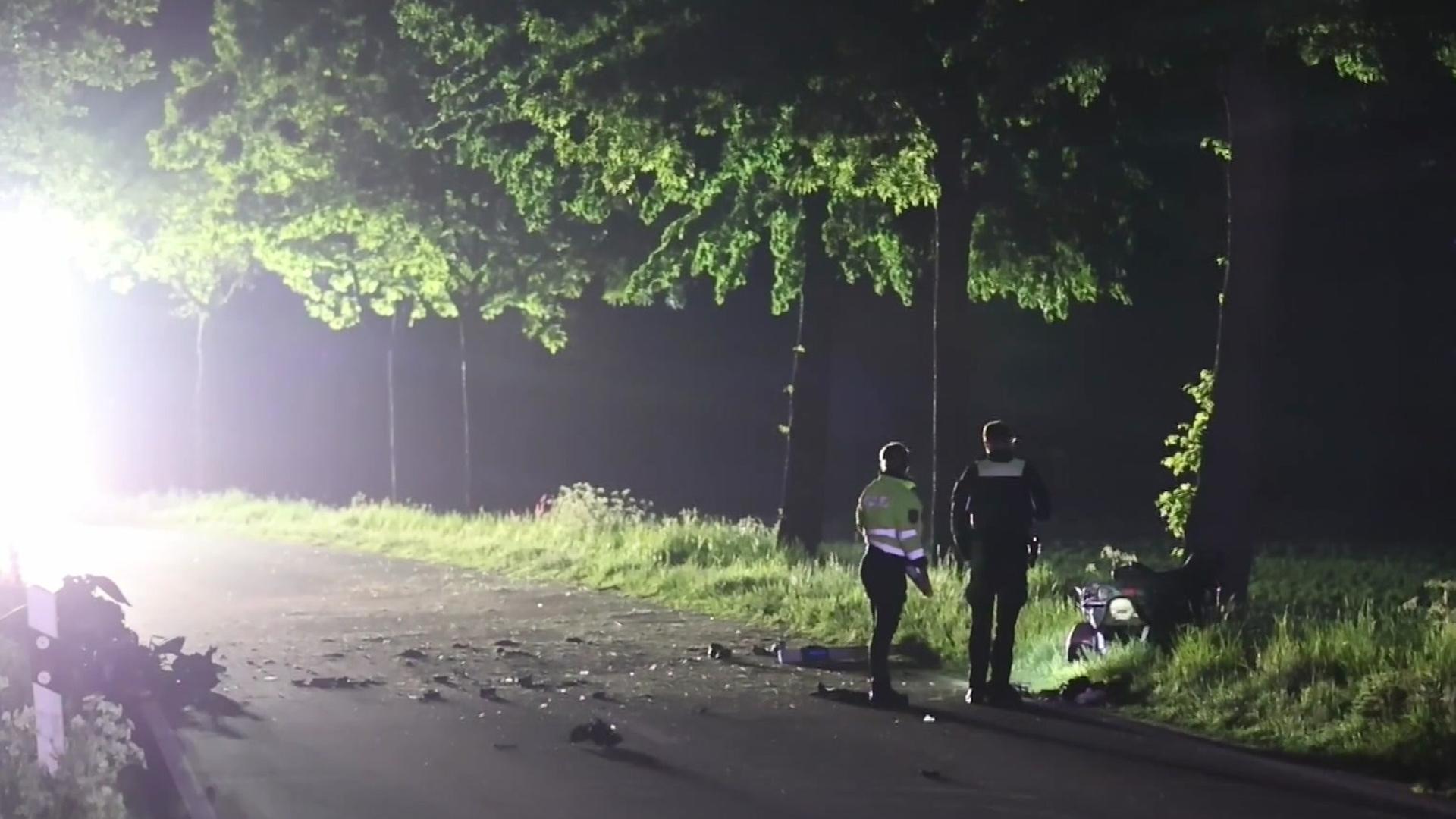 Nach einem Unfall stehen Polizeikräfte auf einer ausgeleuchteten Straße und begutachten Fahrzeugteile. | TeleNewsNetwork