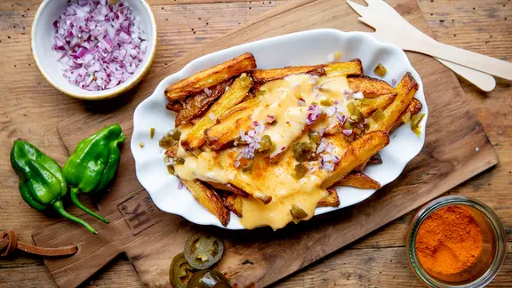 Pommes frites mit Käse-Chilisoße auf einem Teller serviert.