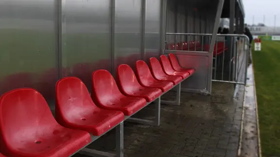 Die Tribüne mit roten Sitzen am Spielfeldrand eines Fußballplatzes.