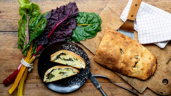 Eine gefüllte Kartoffelrolle und Mangold liegen auf einem Holztisch | NDR, Claudia Timmann Eine gefüllte Kartoffelrolle und Mangold liegen auf einem Holztisch