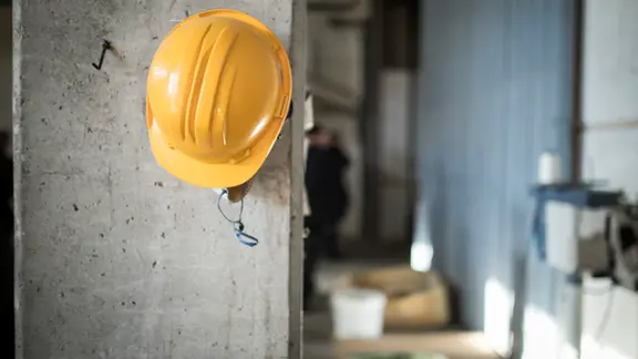 Ein Schutzhelm hängt an einer Säule auf einer Baustelle.
