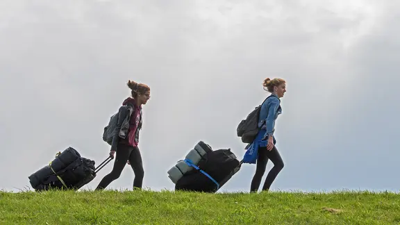 Zwei junge Mädchen gehen mit Gepäck auf einem Deich entlang. | picture alliance , Ingo Wagner Zwei junge Mädchen gehen mit Gepäck auf einem Deich entlang.