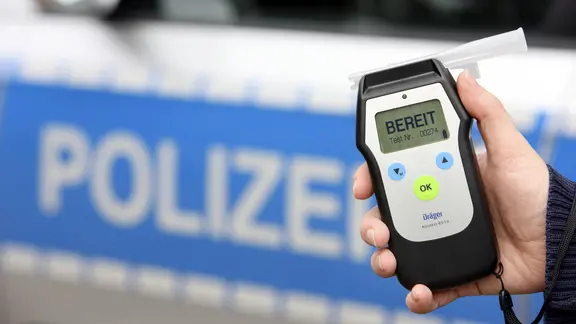 Ein Polizist hält ein Atemalkohol-Messgerät in der Hand