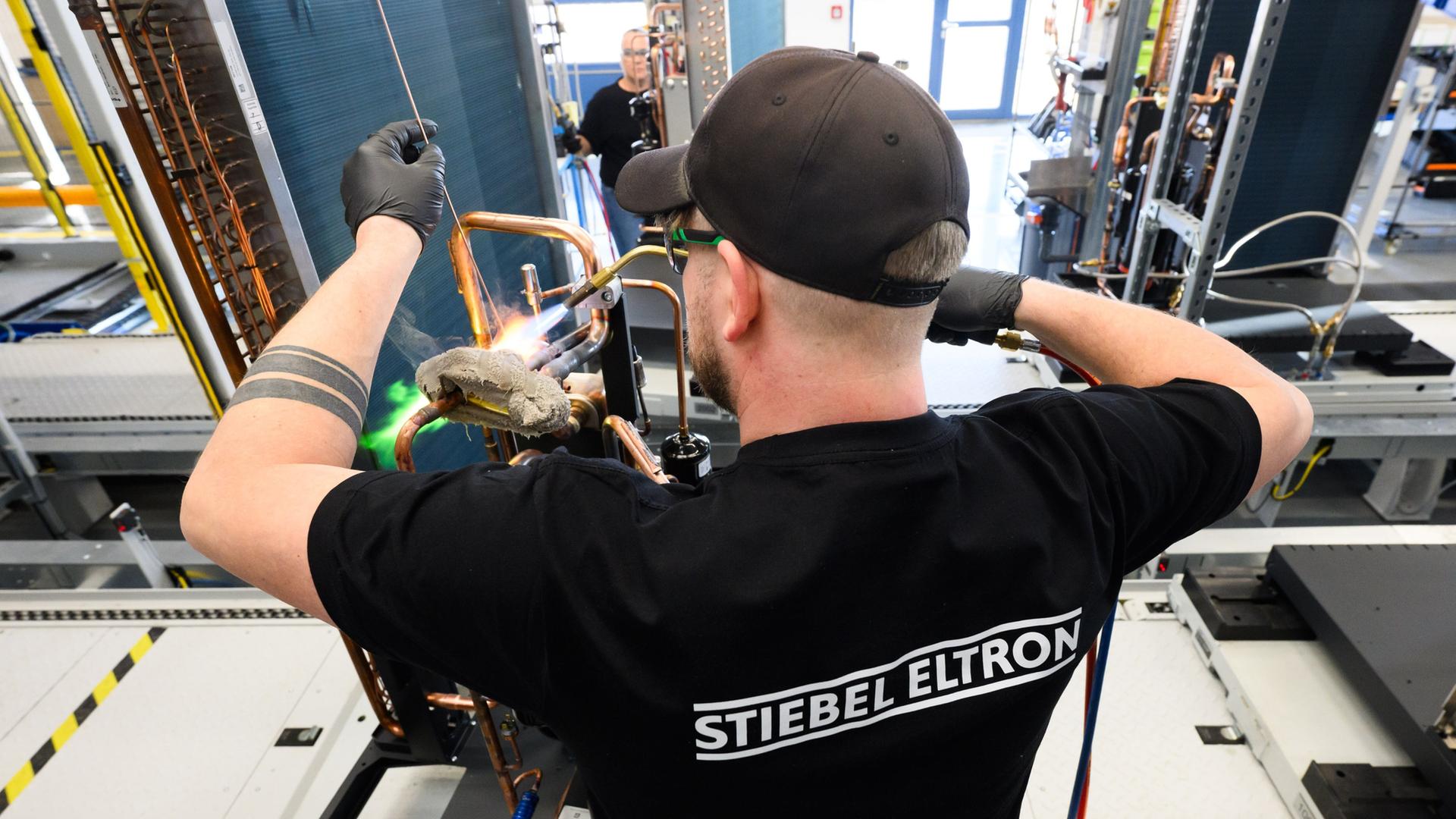 Ein Mitarbeiter von Stiebel Eltron arbeitet am Kältekreislauf einer Wärmepumpe. | picture alliance/dpa, Julian Stratenschulte