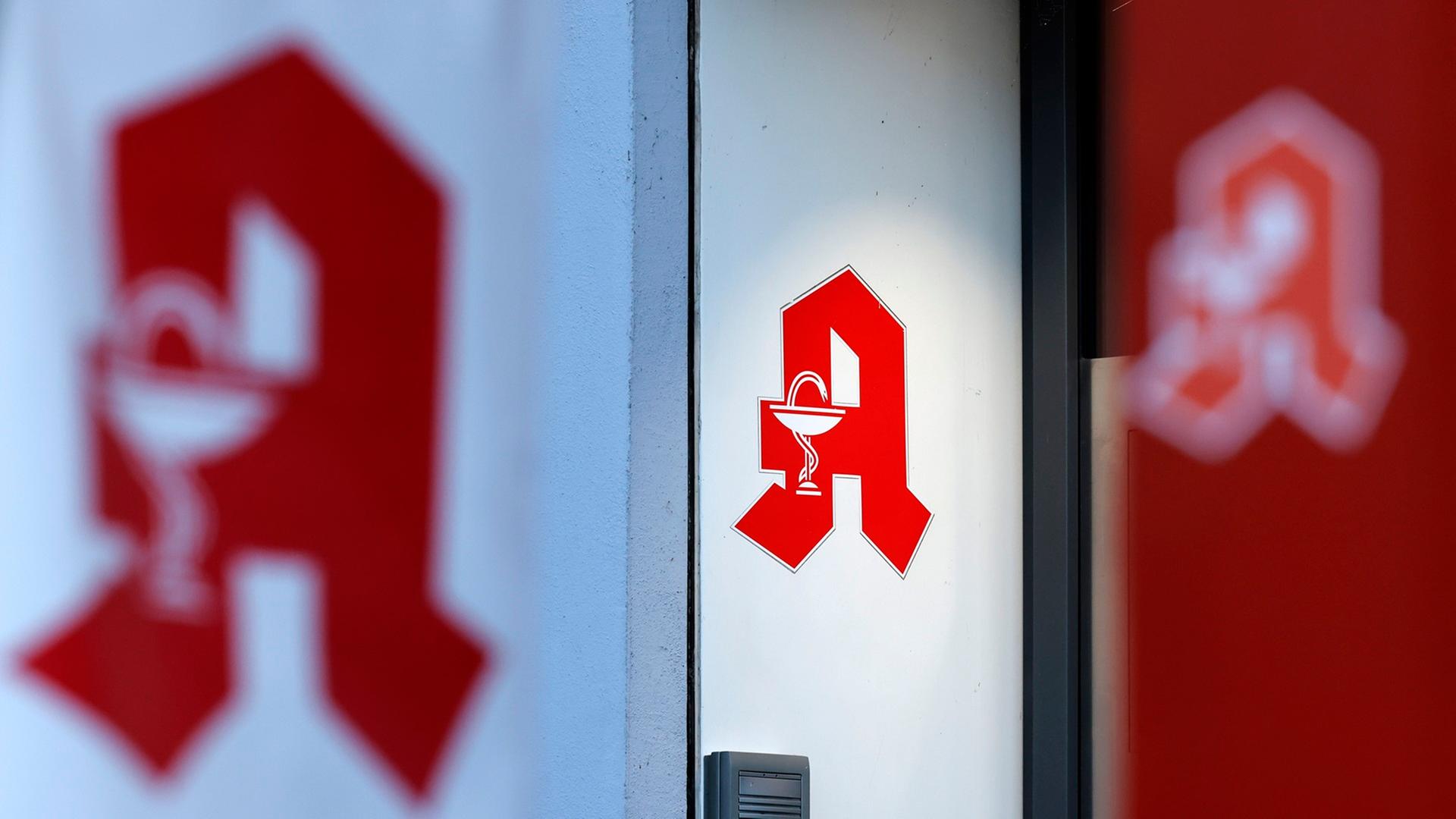 Das Logo einer Apotheke auf einer Wand und umgebenden Aufstellern und Pfeilern. | picture alliance / Panama Pictures | Christoph Hardt