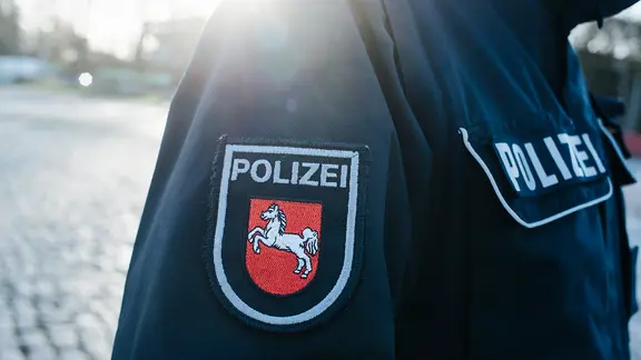 Auf dem Jackenärmel einer blauen Polizeiuniform ist das niedersächsische Wappen aufgenäht.