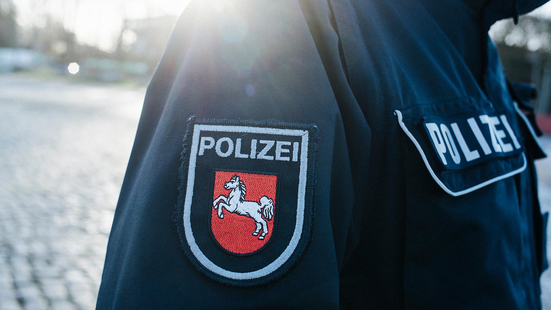 Auf dem Jackenärmel einer blauen Polizeiuniform ist das niedersächsische Wappen aufgenäht. | NDR, Julius Matuschik