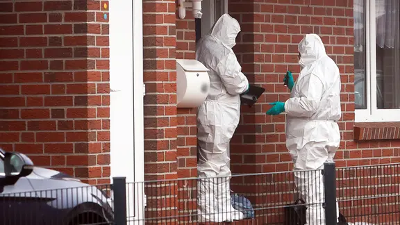 Beamte der Spurensicherung stehen im Emder Stadtteil Larrelt vor einem Einfamilienhaus. | picture alliance / dpa, Jens Doden Beamte der Spurensicherung stehen im Emder Stadtteil Larrelt vor einem Einfamilienhaus.