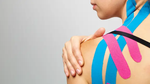 Eine Frau mit Kinesiotapes auf der Schulter