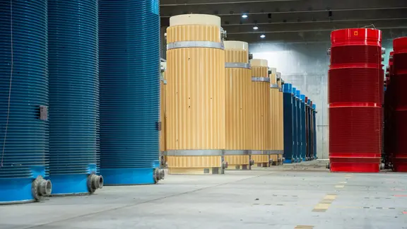 Blaue, beige und rote Behälter mit hochradioaktivem Atommüll stehen im Zwischenlager Gorleben.