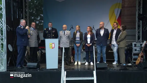 Bei einer Veranstaltung zum Veteranentag in Kiel stehen Menschen auf einer Bühne