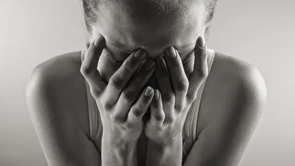 Eine Frau hält sich die Hände vor ihr Gesicht.