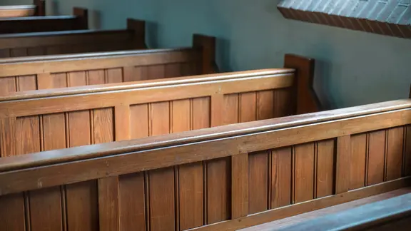 Kirchenbänke aus Holz stehen in einer Kirche